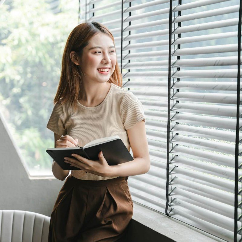 smiling-asian-woman-holding-a-note-in-hand-and-standing-near-window-startup-business-asian-woman-onl-r0zqwhf5frx45od5pju9nj75tegg2ng5p99rxgpav4 --2